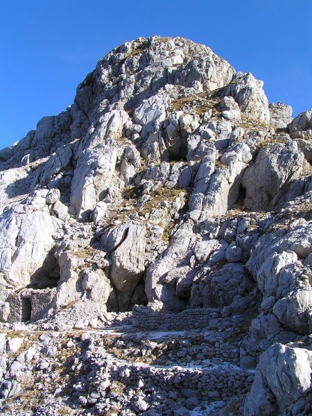 Ostanki italijanskih vojaških zavetišč pod vrhom Skutnika ( 2074 m ); prek sedla pod vrhom