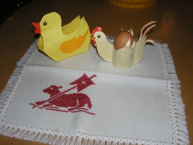 Račka in kokoška iz barvnega papirja na velikonočnem prtičku.
